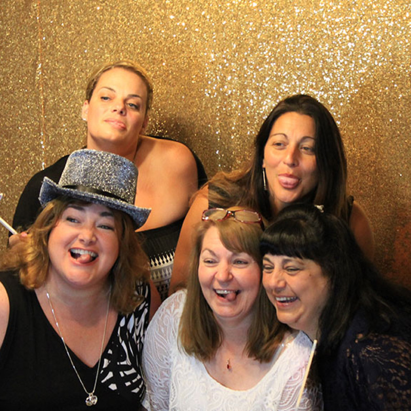 women in a photobooth with a gold background