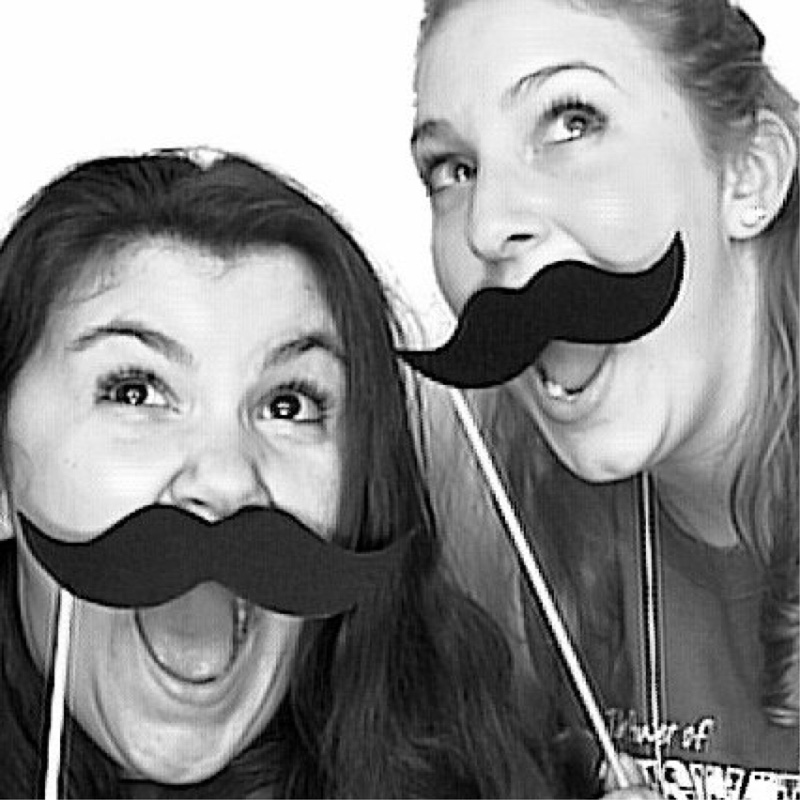 women posing with mustache props in photobooth