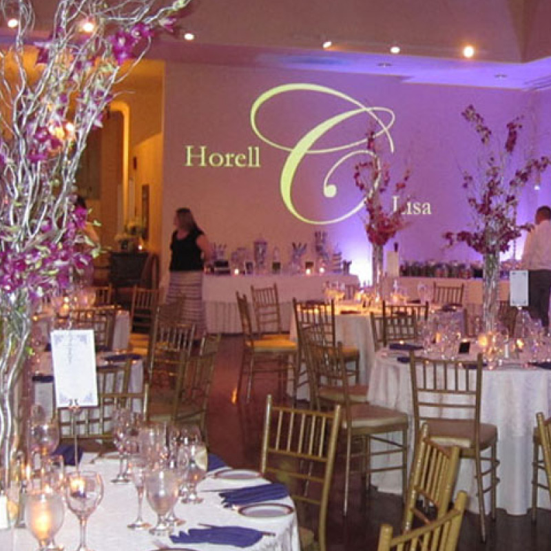 wedding reception setup with couples name in lights on the wall