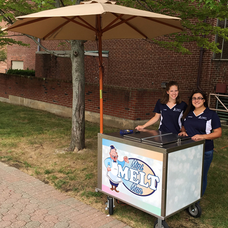 two women working at a mini melt man cart