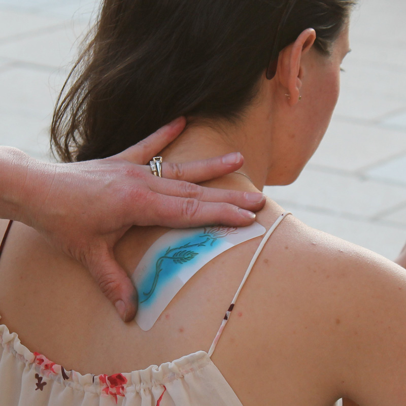 woman getting an airbrush tattoo on her shoulder