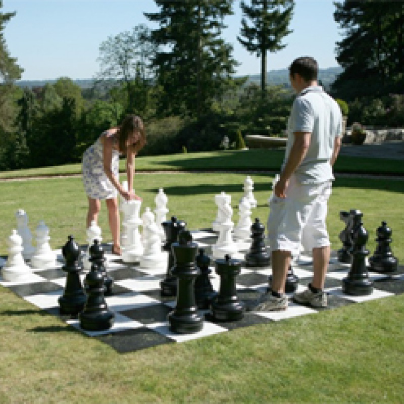 man and woman playing giant chess