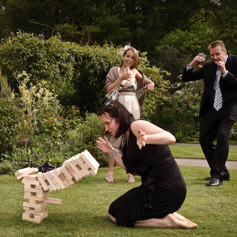 woman watching giant jenga game fall over