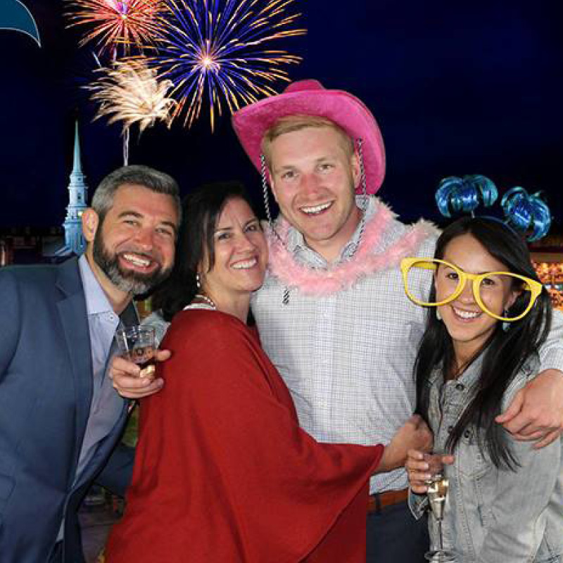 people in a photobooth with a fireworks backdrop